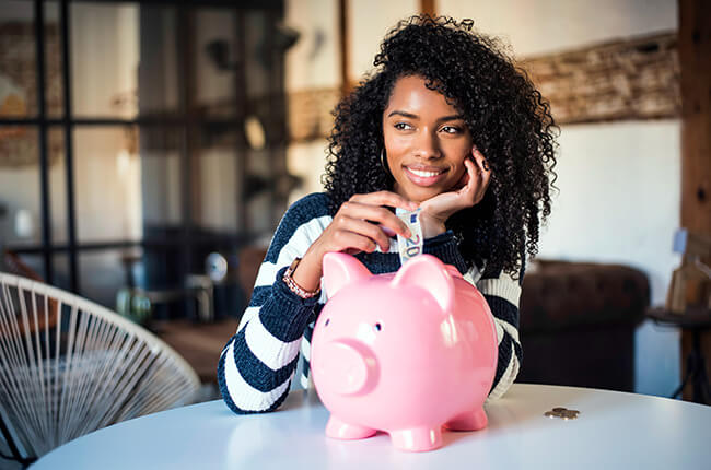 Black woman with savings piggy bank depositing coints